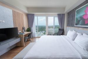 ein Hotelzimmer mit großem Bett und Schreibtisch in der Unterkunft Kamala Bali Resort in Nusa Dua