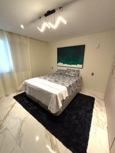 a bedroom with a bed and a painting on the wall at Luxor Oceanfront Suite Smart Apartment Beachfront Superb 9,2 in Guarujá +12 photos