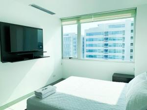 a bedroom with a tv and a bed and a window at Departamento 2 habitaciones frente al Moll del Sol in Guayaquil