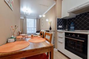 a kitchen with a wooden table with chairs and an oven at Абрикосовое парфе in Astana