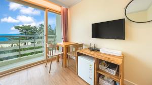 a room with a desk and a tv and a window at Gangneng badapunggeong Pension in Gangneung
