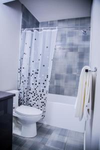 Un baño con inodoro y cortina de ducha. en 2 bedroom basement Suite, en Edmonton