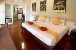 a bedroom with a large bed with yellow pillows at Pinnacle Samui Resort in Mae Nam