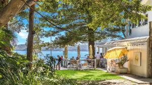 a group of people sitting at a table on the patio of a house at Beachside Escape At Pearl Beach in Pearl Beach