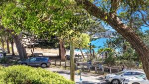 a parking lot with cars parked next to a beach at Beachside Escape At Pearl Beach in Pearl Beach