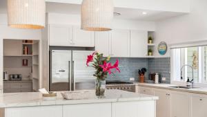 a white kitchen with a vase of flowers on a counter at Beachside Escape At Pearl Beach in Pearl Beach