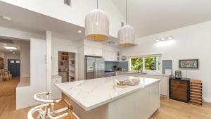 a kitchen with white counters and a large island at Beachside Escape At Pearl Beach in Pearl Beach +13 photos