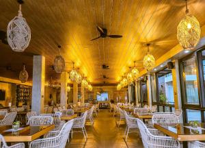un restaurant avec des plafonds en bois et des tables et des chaises blanches dans l'établissement Casa Escondida Anilao Resort And Dive Center, à Mabini