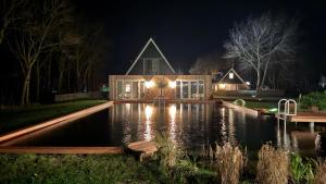 a house with a pond in front of it at night at Wiltsangh Texel Tuinsuite Light in De Waal
