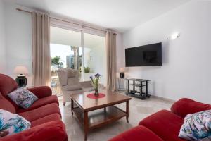 ein Wohnzimmer mit zwei roten Sofas und einem Tisch in der Unterkunft Apartamento de lujo a 30m playa in Estepona