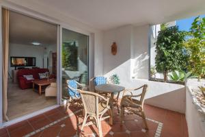 einen Balkon mit Tisch und Stühlen und ein Wohnzimmer in der Unterkunft Apartamento de lujo a 30m playa in Estepona