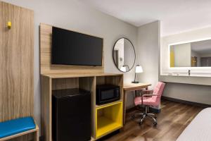 une chambre d'hôtel avec une télévision et un bureau avec une chaise dans l'établissement Days Inn by Wyndham Memphis at Graceland, à Memphis