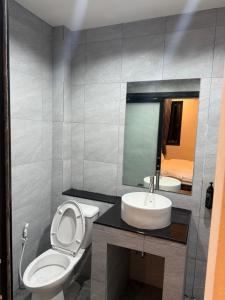 a bathroom with a toilet and a sink and a mirror at โรงแรมช้างใหญ่ใจดี in Yasothon