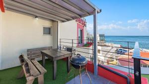 a balcony with a table and a grill and the ocean at Gangneung Glad Pension in Gangneung