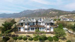 an aerial view of a large house with mountains in the background at Ganghwa Western Beach Pension in Incheon