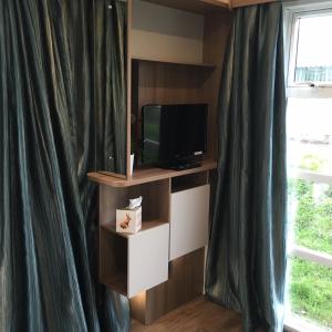 einen TV auf einem Regal neben einem Fenster in der Unterkunft Parkknott Retreat in Askam in Furness