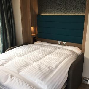 a bed with white sheets and a blue headboard at Parkknott Retreat in Askam in Furness