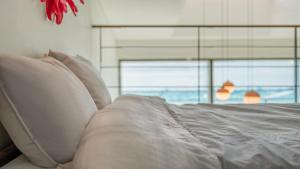 a white bed with white pillows and a window at Sacheon Bichae Pension in Sacheon