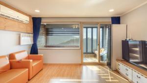 a living room with a couch and a television at Wonju Quirinale Pension in Wonju