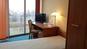 a hotel room with a desk with a television and a window at Noclegi Apro in Gdańsk