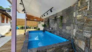 江陵市Gangneung ggabinejip hanok pension的一座带石墙和蓝色海水的室外游泳池 更多18张照片