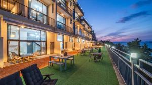 a balcony of a building with tables and chairs at Yeosu dasi bom pension in Yeosu