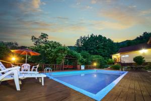 a swimming pool with two chairs and an umbrella at Gapyeong Ashely Pension in Gapyeong