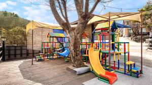 a playground with a colorful play set next to a tree at Namyangju HAIMOM Family Pension Black in Namyangju