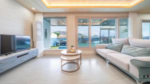 a living room with a couch and a tv at Namhae Eagless Poolvilla Pension in Namhae