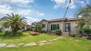 a house with a yard with a bench and palm trees at lalapipo jeju in Jeju +4 photos