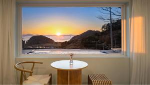 d'une fenêtre avec une table et une vue sur le coucher du soleil. dans l'établissement Namhae U9Stay, à Namhae