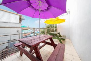 a wooden picnic table with two umbrellas on a balcony at Gangneung The ciel Spa Pension in Gangneung
