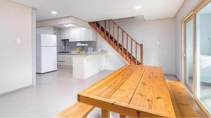 a kitchen with a wooden table and a staircase at Jeju CountryFarmpension in Seogwipo