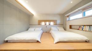 Dos camas en una habitación pequeña con ventana. en Gyeongju Adria Stay Pension, en Gyeongju