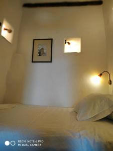 Un dormitorio con una cama con dos luces en la pared. en Sigalas House, Sikinos Island, en Síkinos