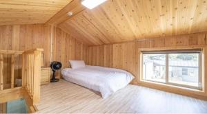 a bedroom with a bed in a wooden room at jeju bijalim pension in Jeju
