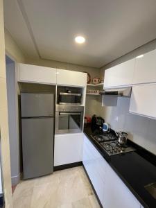 a kitchen with white cabinets and a stainless steel refrigerator at Marina Agadir appartement standing 90m2 + piscine in Agadir