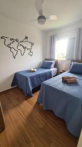 a room with two beds with blue sheets and a map on the wall at Refúgio do Viajante in Espirito Santo Do Pinhal