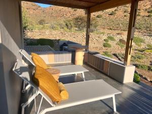 a porch with a bench and a table with pillows at Aardvark Bioreserve in Ladismith