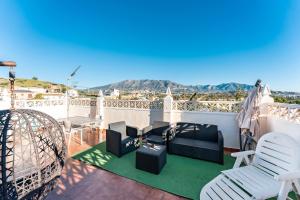 a balcony with white chairs and a table at Palm House in Fuengirola