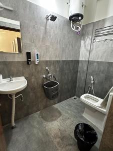 a bathroom with a sink and a toilet and a mirror at Trinetra Homes 102 in Bengaluru