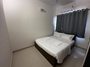 a small bedroom with a bed and a window at Trinetra Homes 102 in Bengaluru