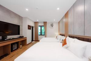 a hotel room with two beds and a flat screen tv at Lam Anh Hotel 8 Ngoại Giao Đoàn BT3-10 in Hanoi