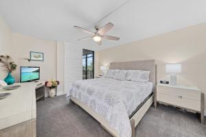 萨尼贝尔Compass Point #243的一间卧室，里面有一张床、一张桌子和一台电视。 更多45张照片