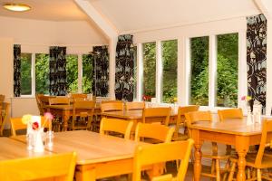 un ristorante con tavoli e sedie in legno e finestre di YHA Grasmere Butharlyp Howe a Grasmere