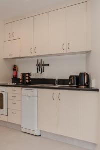 a white kitchen with white cabinets and appliances at The Terrace CBD Apt for Work & Play in Wellington