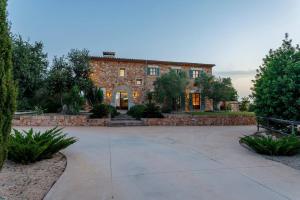 a large brick house with a stone driveway at Cas Coix Jacuzzi, gym & pool in Biniali