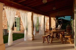 a porch with white curtains and a wooden table at Cas Coix Jacuzzi, gym & pool in Biniali