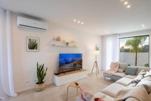 ein weißes Wohnzimmer mit einem Sofa und einem TV in der Unterkunft ISULATRAVEL - Villa Nerissa in Pozzallo