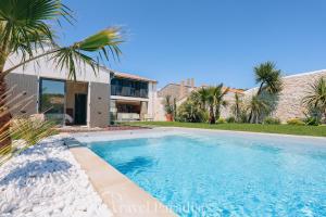 a swimming pool in front of a house at Villa Saint Exupery in Le Bois-Plage-en-Ré